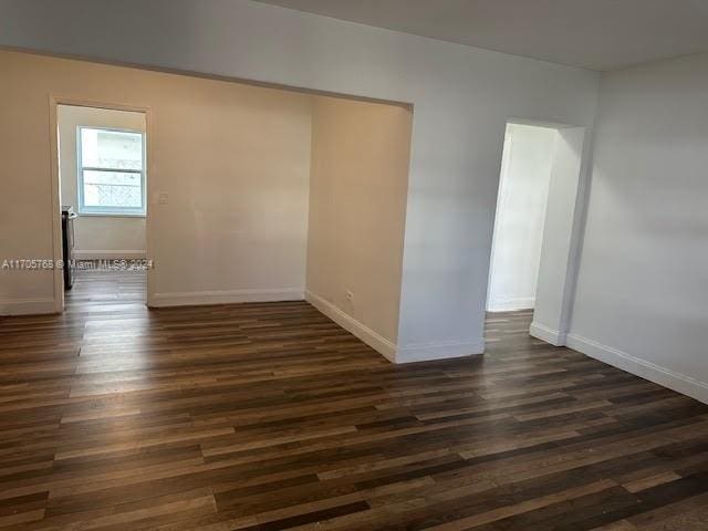 unfurnished room with dark wood-type flooring