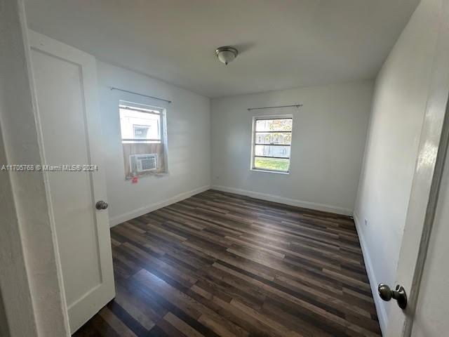 unfurnished room with cooling unit and dark wood-type flooring