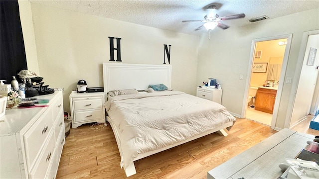 bedroom featuring ensuite bath, ceiling fan, light hardwood / wood-style floors, and a textured ceiling