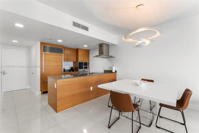 kitchen featuring a kitchen breakfast bar, hanging light fixtures, wall chimney exhaust hood, paneled fridge, and cooktop