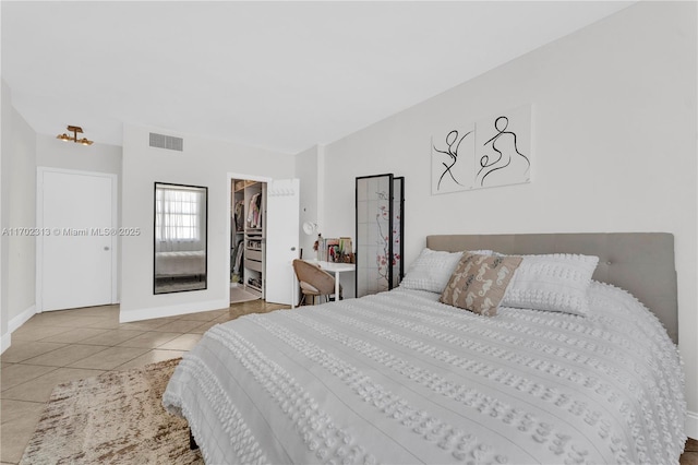 bedroom with a walk in closet, light tile patterned floors, and a closet