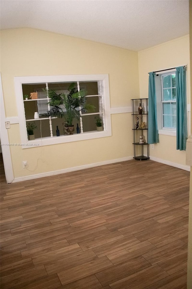 empty room with a textured ceiling, dark hardwood / wood-style flooring, and lofted ceiling