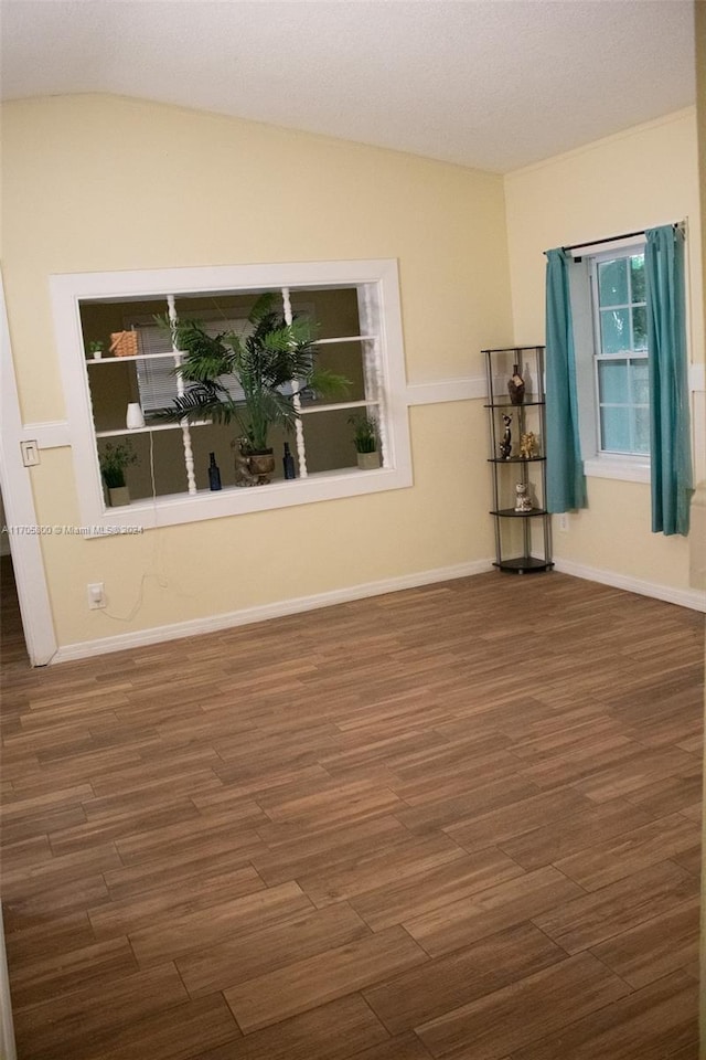 unfurnished room featuring dark hardwood / wood-style floors, a textured ceiling, and vaulted ceiling