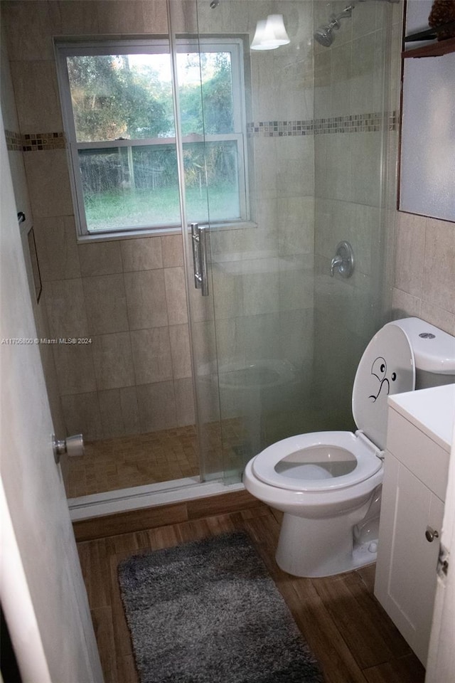 bathroom with walk in shower, hardwood / wood-style floors, toilet, vanity, and tile walls