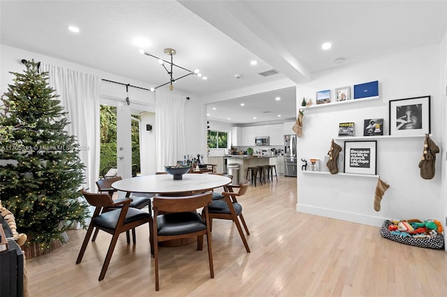 dining room featuring beamed ceiling, a notable chandelier, light wood-type flooring, and french doors