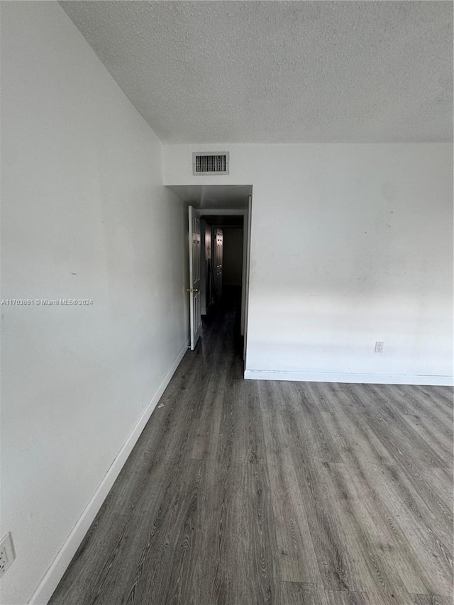 spare room featuring dark hardwood / wood-style flooring and a textured ceiling