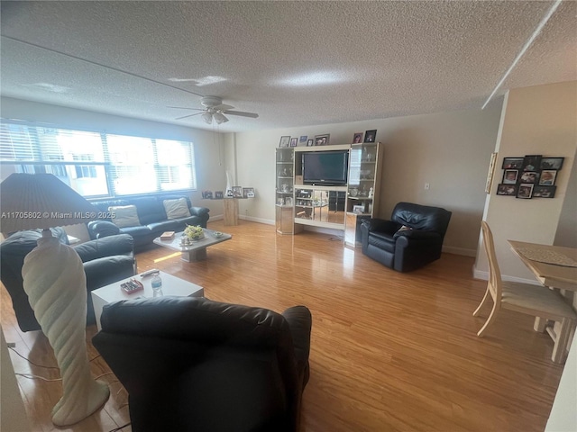 living room featuring wood-type flooring, ceiling fan, and a textured ceiling