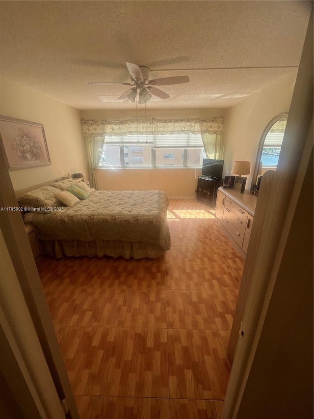 bedroom with ceiling fan, wood-type flooring, and a textured ceiling