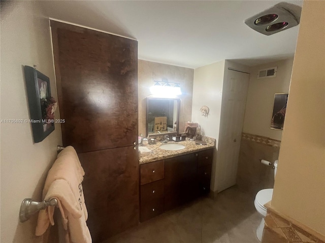 bathroom with tile patterned floors, vanity, toilet, and tile walls