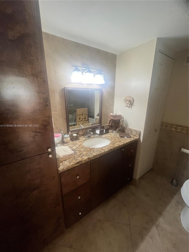 bathroom with vanity, tile walls, tile patterned floors, and toilet