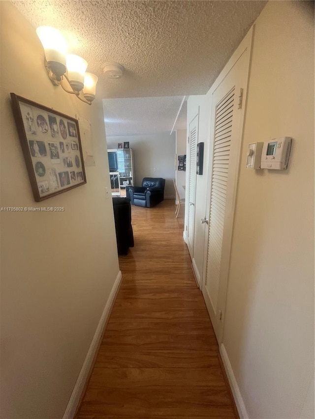 hall with hardwood / wood-style flooring and a textured ceiling