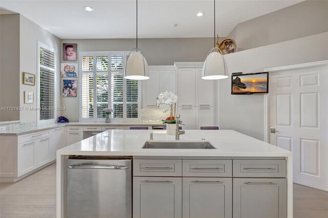 kitchen featuring white cabinets, sink, light wood-type flooring, and hanging light fixtures