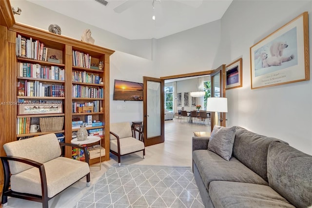 sitting room with ceiling fan, french doors, high vaulted ceiling, and light wood-type flooring