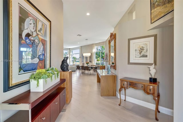 corridor with an inviting chandelier and light hardwood / wood-style flooring