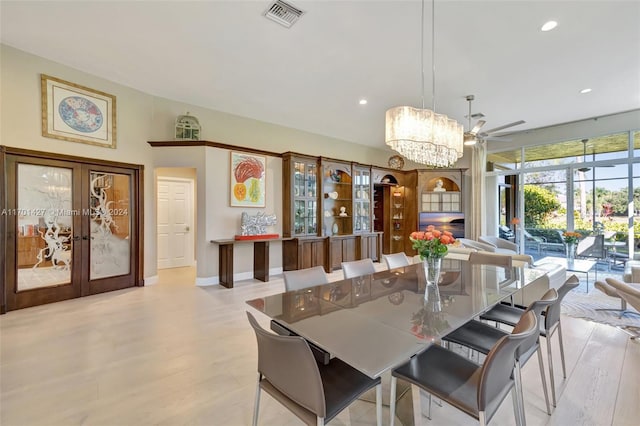 dining space featuring ceiling fan with notable chandelier, french doors, and light wood-type flooring