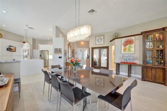 dining room with an inviting chandelier, light hardwood / wood-style flooring, and french doors