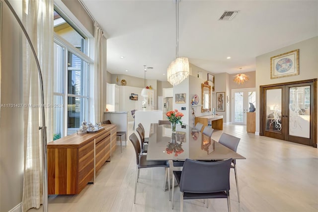 dining space featuring french doors, a chandelier, and light wood-type flooring