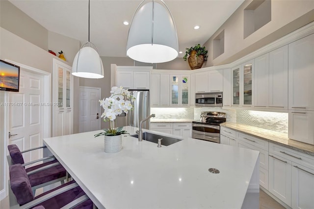 kitchen featuring sink, an island with sink, stainless steel appliances, and decorative light fixtures