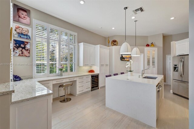 kitchen featuring pendant lighting, white cabinets, sink, stainless steel refrigerator with ice dispenser, and beverage cooler