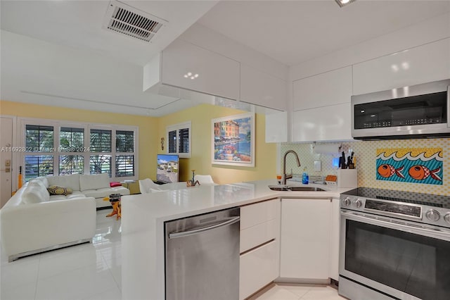 kitchen with backsplash, white cabinets, sink, kitchen peninsula, and stainless steel appliances