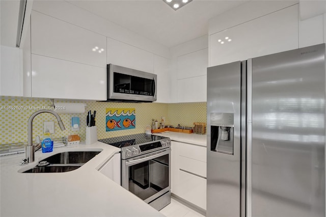 kitchen featuring white cabinets, appliances with stainless steel finishes, backsplash, and sink