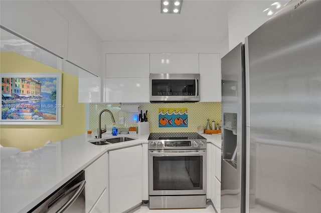 kitchen with decorative backsplash, white cabinetry, sink, and appliances with stainless steel finishes