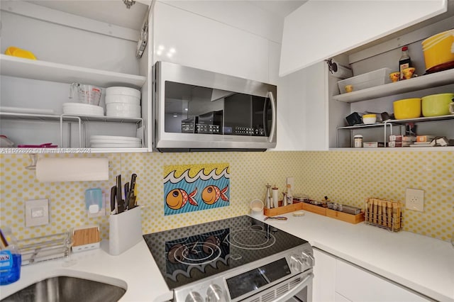 kitchen with tasteful backsplash, white cabinets, and stainless steel appliances