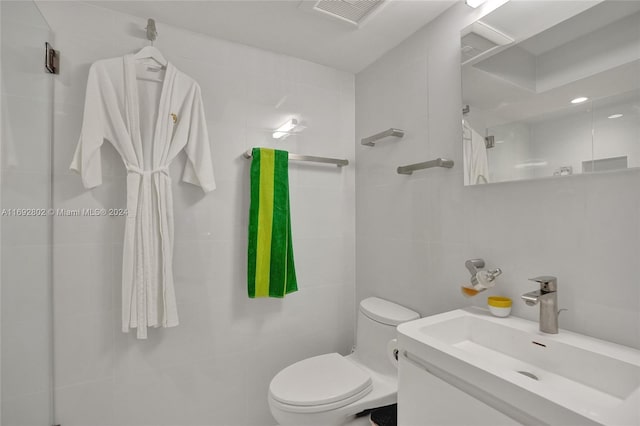 bathroom with backsplash, tiled shower, toilet, vanity, and tile walls