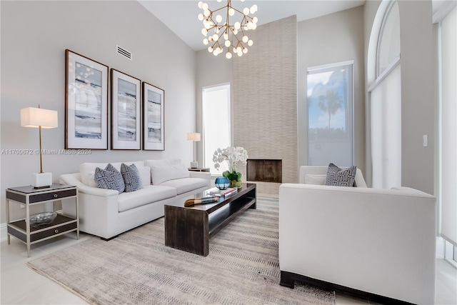 living room featuring a chandelier, a fireplace, a healthy amount of sunlight, and a high ceiling