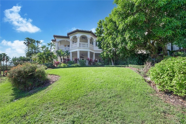 view of yard with a balcony and ceiling fan