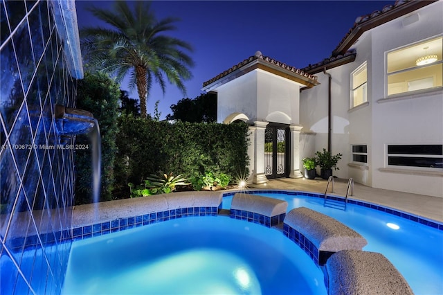 pool at night with an in ground hot tub and pool water feature