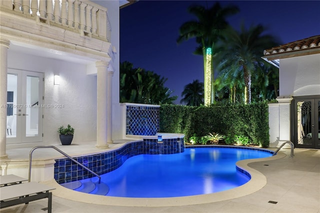 pool at twilight with a jacuzzi, french doors, and a patio area