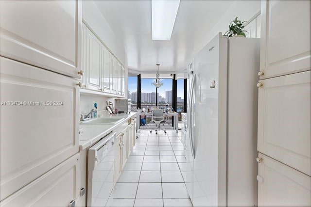 kitchen with white appliances, white cabinets, sink, light tile patterned floors, and decorative light fixtures