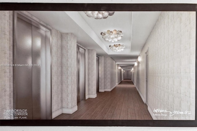 corridor with hardwood / wood-style floors, a raised ceiling, and a chandelier