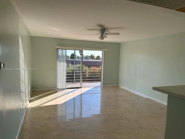 tiled spare room with ceiling fan