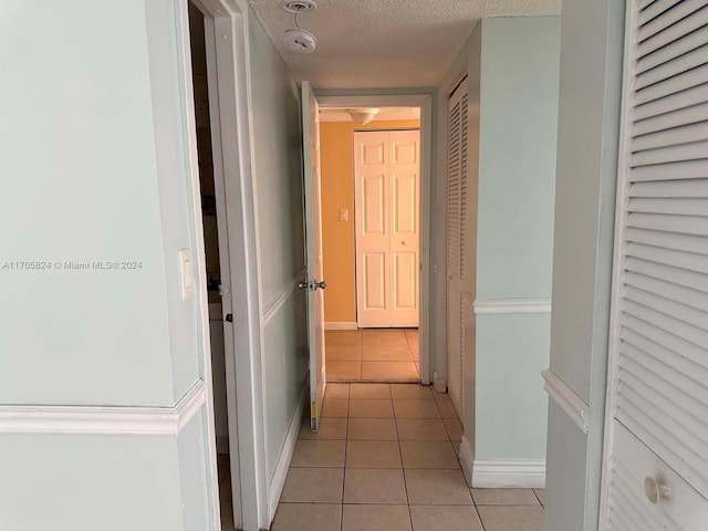 hall with light tile patterned floors and a textured ceiling