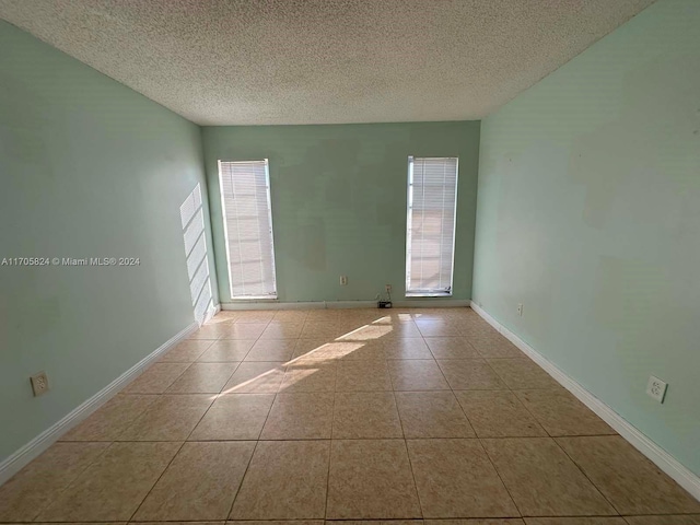 tiled empty room featuring plenty of natural light and a textured ceiling