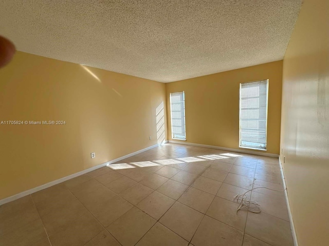 tiled spare room featuring a textured ceiling