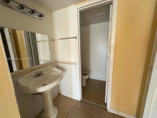 bathroom featuring tile patterned floors, a textured ceiling, and toilet