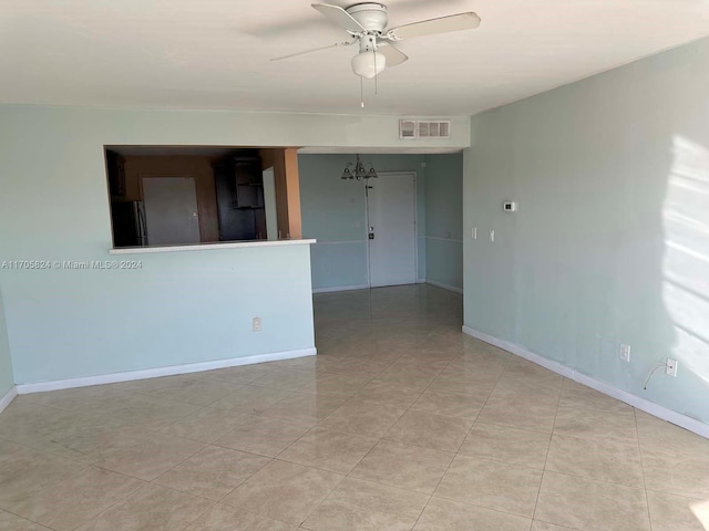 spare room with ceiling fan with notable chandelier and light tile patterned flooring