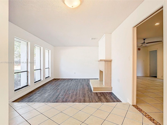 unfurnished living room with ceiling fan, wood-type flooring, and a textured ceiling