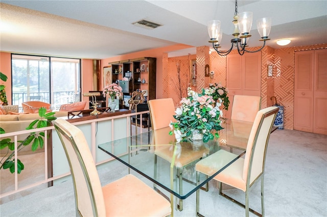 dining area with a textured ceiling, light carpet, and a chandelier