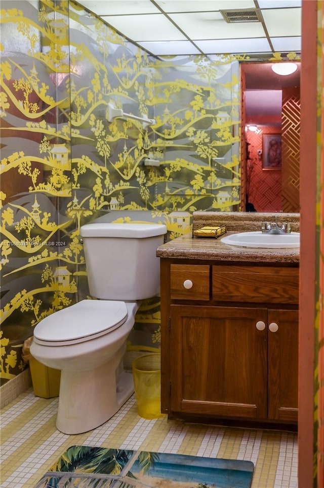 bathroom featuring vanity, a drop ceiling, and toilet