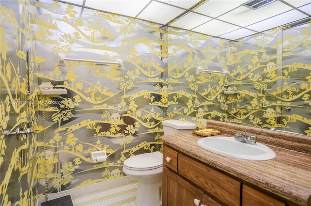 bathroom featuring vanity, a drop ceiling, and toilet