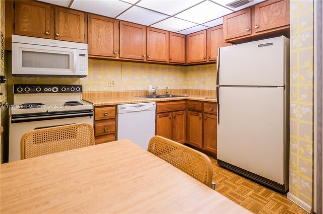 kitchen featuring white appliances, sink, and light parquet flooring