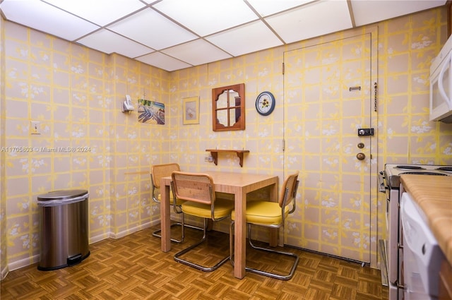 dining room with dark parquet flooring and a drop ceiling