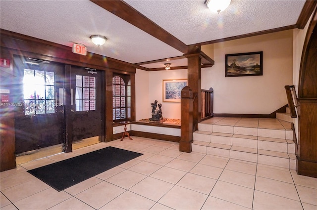 tiled entryway featuring ornamental molding and a textured ceiling