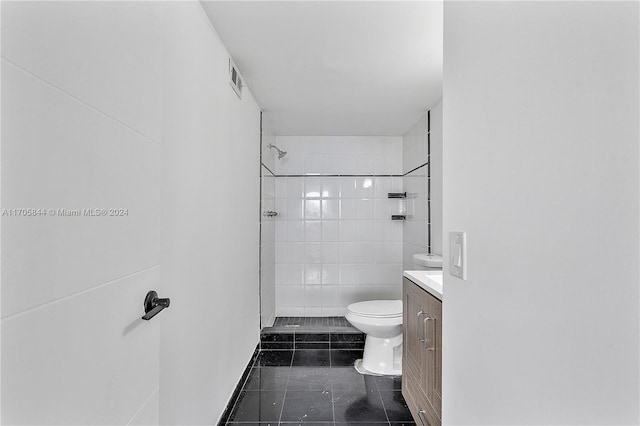 bathroom featuring a tile shower, vanity, tile walls, tile patterned flooring, and toilet