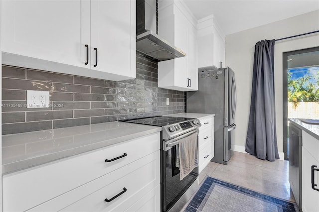 kitchen featuring backsplash, white cabinets, wall chimney range hood, and appliances with stainless steel finishes