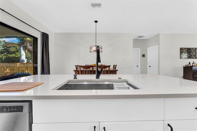 kitchen featuring stainless steel dishwasher, decorative light fixtures, white cabinets, and sink